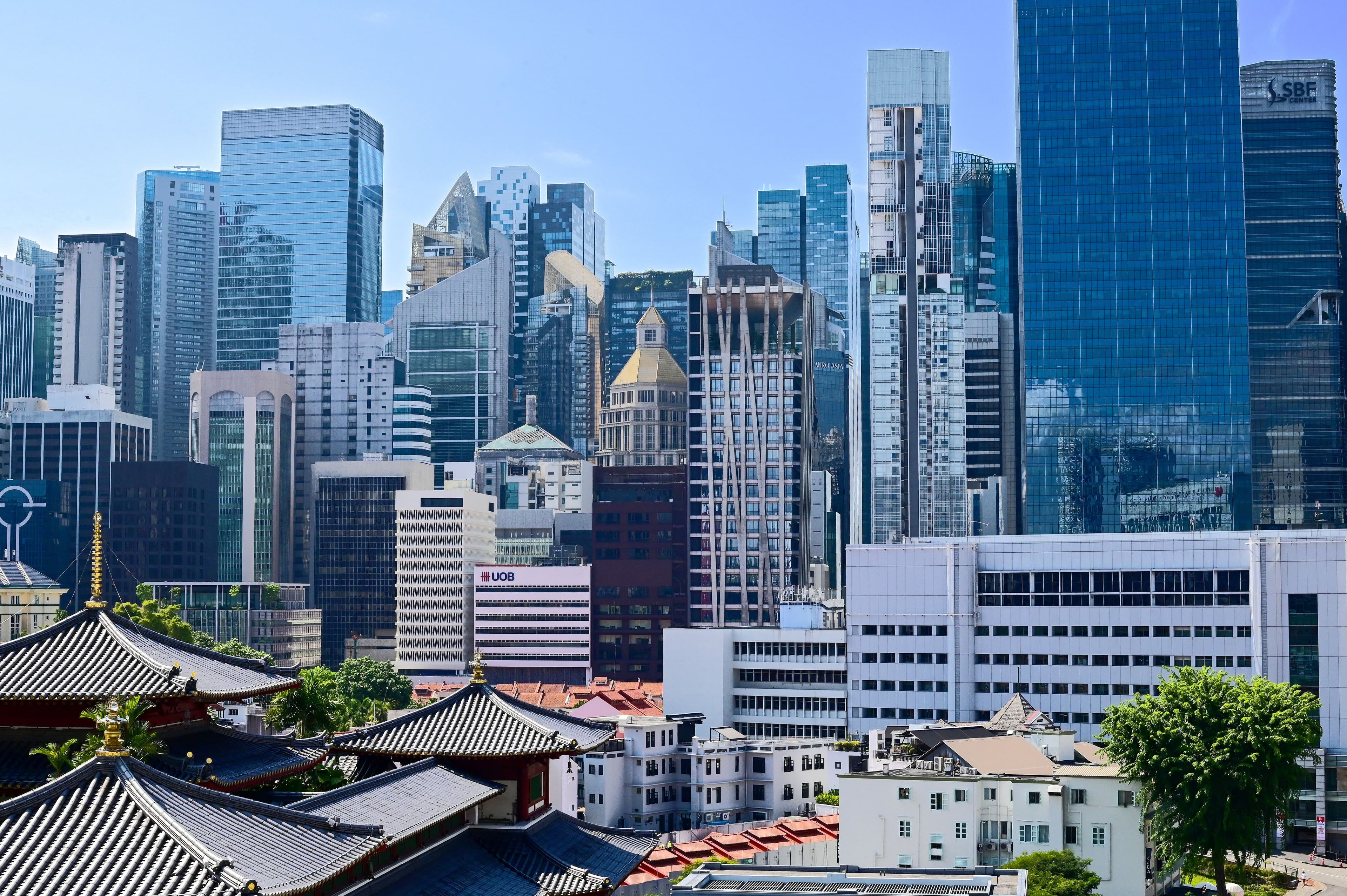 Singapore's downtown skyline of glass and steel skyscrapers rising above a traditional temple roof